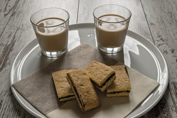 biscotti farciti al cioccolato fondente e bicchiere caffè e latte