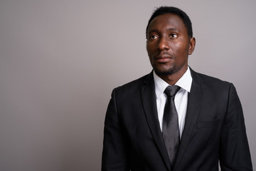 Young handsome African businessman against gray background