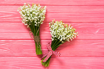 Beautiful bouquet of flowers lily of the valley on pink wooden table with copy-space from above. top view, flat lay