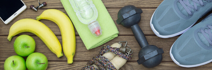 Top view of Healthy lifestyle concept, sport equipments and fresh foods on wood background.  Web...