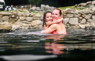 Mother and daughter relaxing in natural thermal water roman spa.