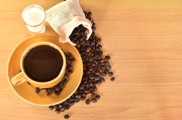 Coffee cup and coffee beans on wooden background.