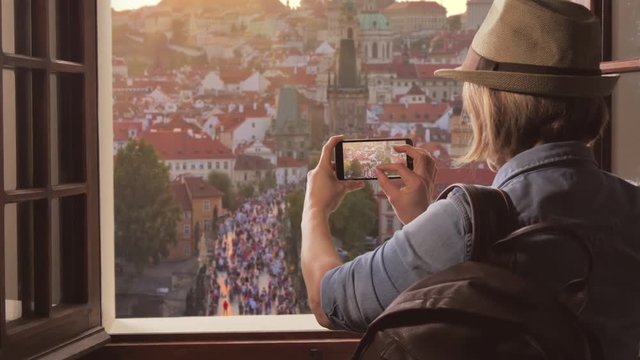 tourist takes photo of prague skyline at sunset,traveler woman photographs charles bridge using smartphone