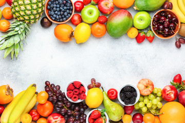 Healthy fruits berries background, strawberries raspberries oranges plums apples kiwis grapes blueberries mango persimmon on the white table, top view, copy space for text, selective focus