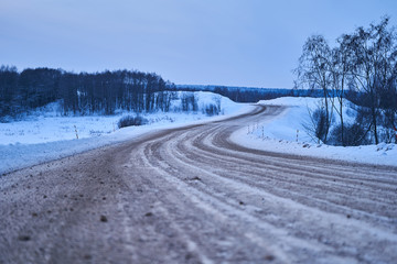 dirt track through a field of snow at dawn or dusk