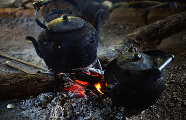 Kettle Smoking on a Grill over a Camp Fire .