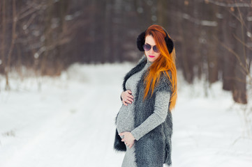 Fototapeta na wymiar Portrait of beautiful pregnant woman in the winter forest