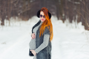 Fototapeta na wymiar Portrait of beautiful pregnant woman in the winter forest