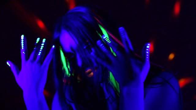 Fashion model girl with colorful fluorescent makeup in neon lights. Female disco dancer in UV light. Night club, party. Slow motion 4K UHD video footage. 3840X2160
