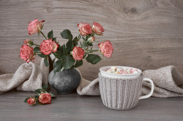Valentines day still life with cup of hot chocolate with marshmallows, pink roses and scarf