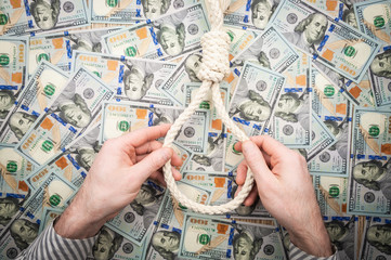 Men's hands with loop of rope on background of dollars. top view