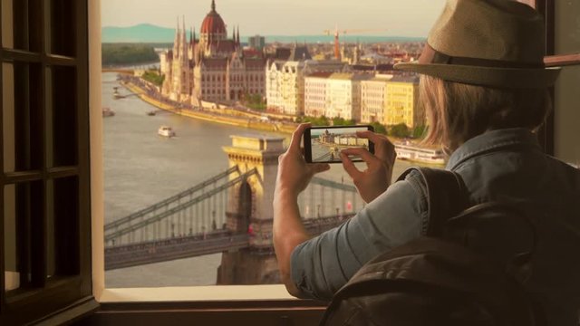 tourist taking picture of budapest skyline,woman traveler photographs parliament chain bridge using smartphone
