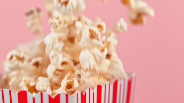 Falling popcorn in super slow motion on pink background.