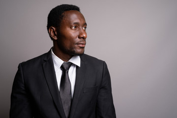 Young handsome African businessman against gray background