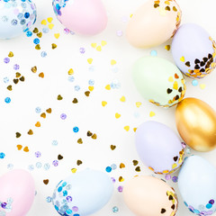 Festive Easter background with decorated eggs, flowers, candy and ribbons in pastel colors on white. Copy space