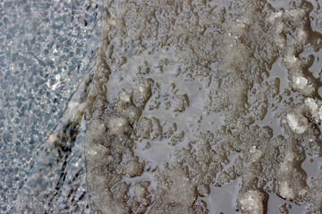 Melting snow asphalt slush water flow puddle dirty street sidewalk