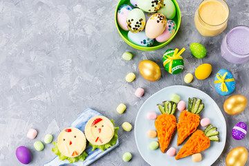 Fototapeta na wymiar Funny colorful Easter food for kids with decorations on table. Easter dinner concept