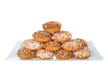 Chocolate and white frosted donuts covered in candy sprinkles piled into a cake pile isolated on white background.