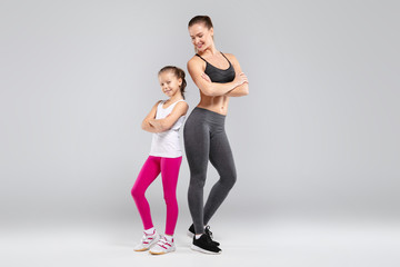 Sportive beautiful woman and her daughter posing on camera