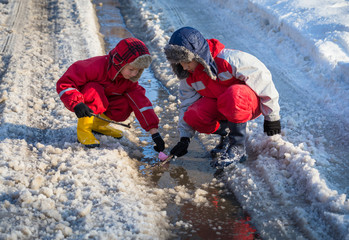 Two boys launching the paper boat at the creek