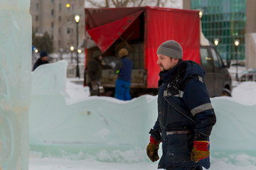 Assembler in overalls on the territory of the ice town