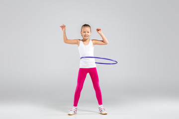Smiling girl doing exercises with hula hoop