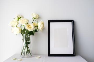 White roses in a glass vase on white table top on white background with copy space for product mockup placement for valentine's day wedding ceremony