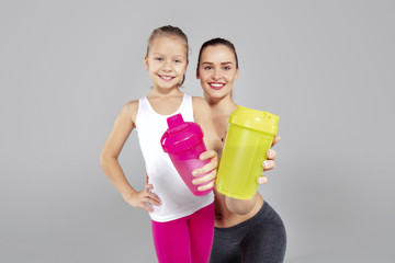 Beautiful woman and her little daughter with thermal mugs