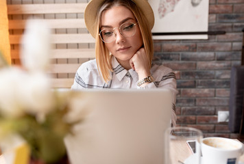 Portrait of young woman using laptop at cafe, she is working on laptop computer at a coffee shop.