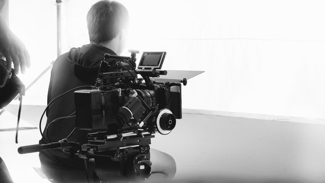 Behind video camera that recording online commercial or web film movie in the big studio production with professional equipment such as high resolution cam and monitors and LED light with crew team
