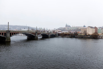 Snowy foggy Prague Lesser Town with gothic Castle above River Vltava, Czech republic