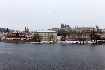 Snowy foggy Prague Lesser Town with gothic Castle above River Vltava, Czech republic