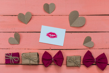 gifts, hearts and a card with a lip print on a pink wooden background