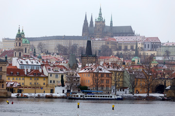 Fototapeta na wymiar Snowy foggy Prague Lesser Town with gothic Castle above River Vltava, Czech republic