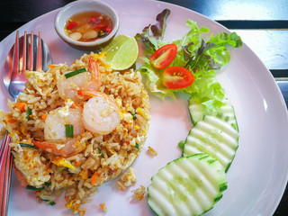 Fried rice with shrimp in a white dish on wood table.