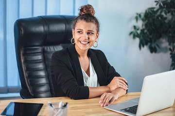 A young girl dressed in business clothes is working on a laptop.
