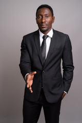 Young handsome African businessman against gray background