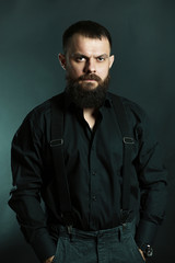 Obraz premium young handsome man with big beard in black t shirt on black background 