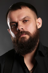 young handsome man with big beard in black t shirt  on black background  