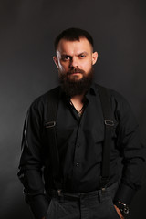 Obraz premium young handsome man with big beard in black t shirt on black background 