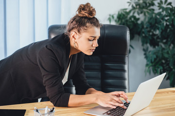 A young girl dressed in business clothes is working on a laptop.