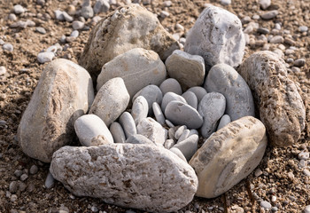 the composition of gray stones of different sizes in the form of a flower on the beach