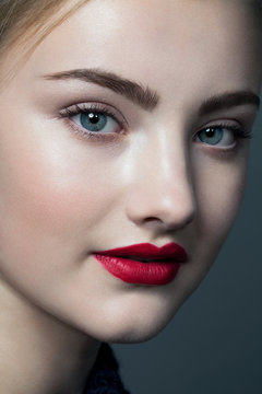 Portrait of a young woman with blue eyes wearing red lipstick, cropped.