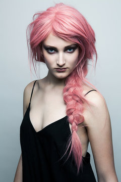 Young woman wearing a pink wig and strong make up, portrait.