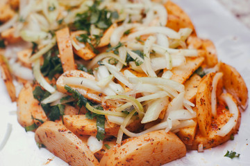 Sliced raw potatoes with onion and green on cooking foil. Ready to cook.