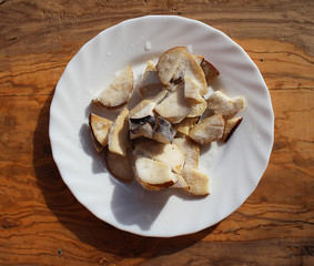 Chopped frozen  Boletus Edulis mushrooms on a white plate from the wood