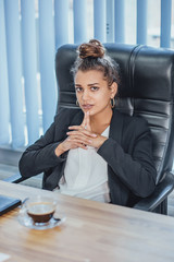A young business stylish girl in the office is working on a laptop.