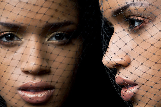 Beautiful, young woman wearing a black birdcage veil reflecting in a mirror, close up.