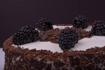 Healthy Vegeterian Blackberry chocolate cake with White Chocolate Buttercream, close up, topping view. Black background.