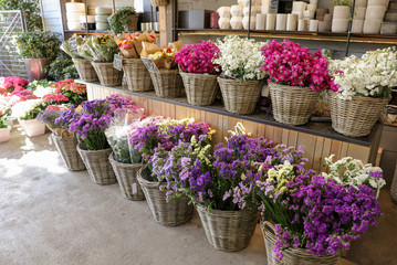 Fototapeta na wymiar In a wicker basket variety of limonium sinuatum and matthiola incana flowers in violet, pink, white colors for sale in the greek flower shop.
